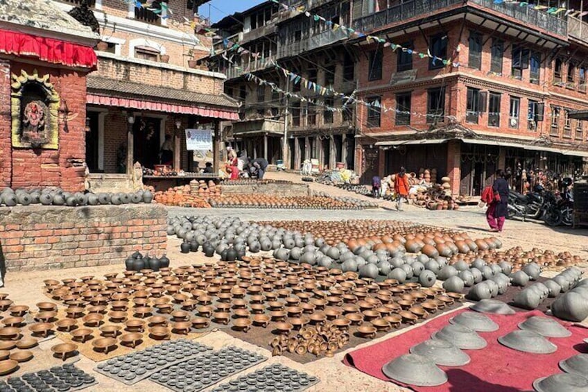 A market with pottery and metal items displayed on the ground. 2