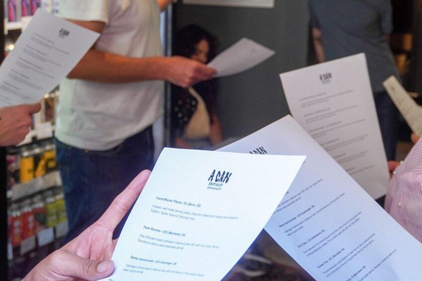 A person holding a paper with text, surrounded by other papers and people in a public space. 4