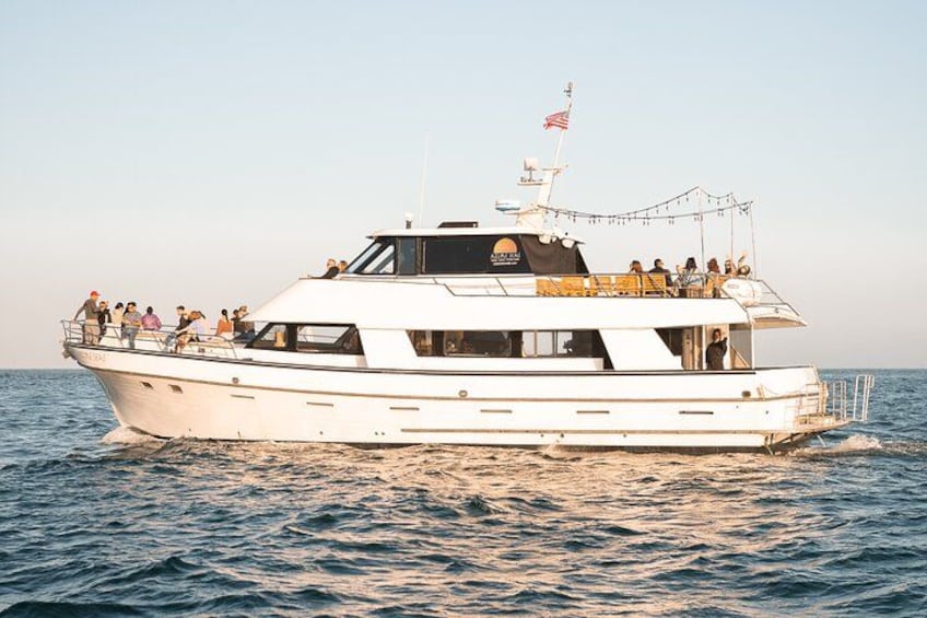 Un yacht blanc, avec des passagers sur le pont, navigue sur des eaux calmes. 2