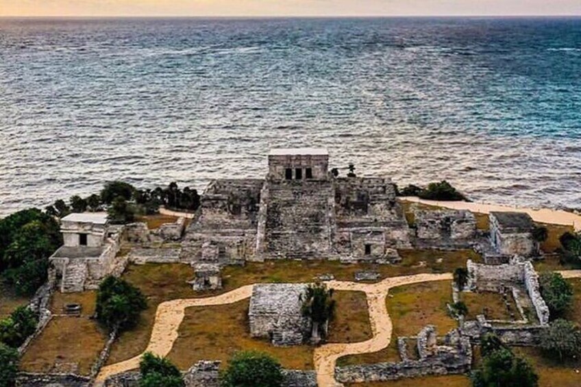 An ancient ruin with a central structure and surrounding pathways, overlooking the sea. 5