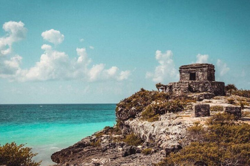 A stone structure on a cliff overlooking turquoise waters. 3