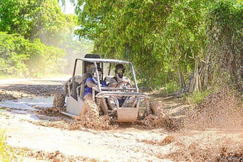 A vehicle navigating a muddy terrain with water on the sides. 2