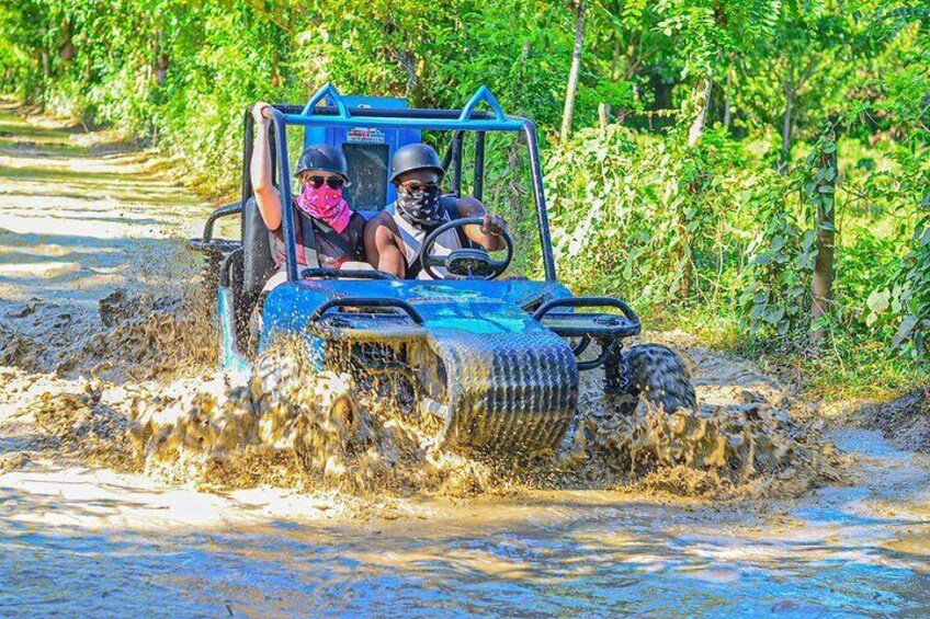 A blue off-road vehicle driving through a muddy water crossing. 3
