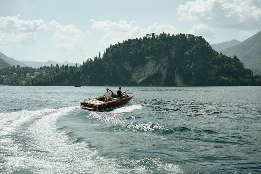 Una barca che scivola su un lago, con un'isola boscosa sullo sfondo. 1