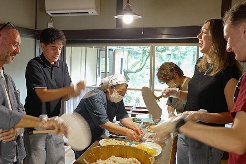 A group of people engaged in a food preparation activity, with a focus on rolling dough. 4