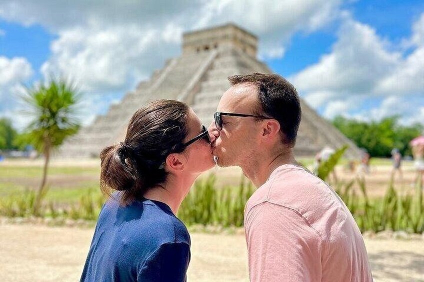 A couple kissing in front of a pyramid. 1
