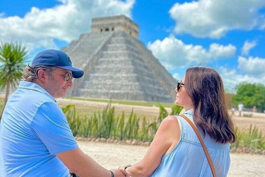 A couple standing in front of a large pyramid-like structure. 5