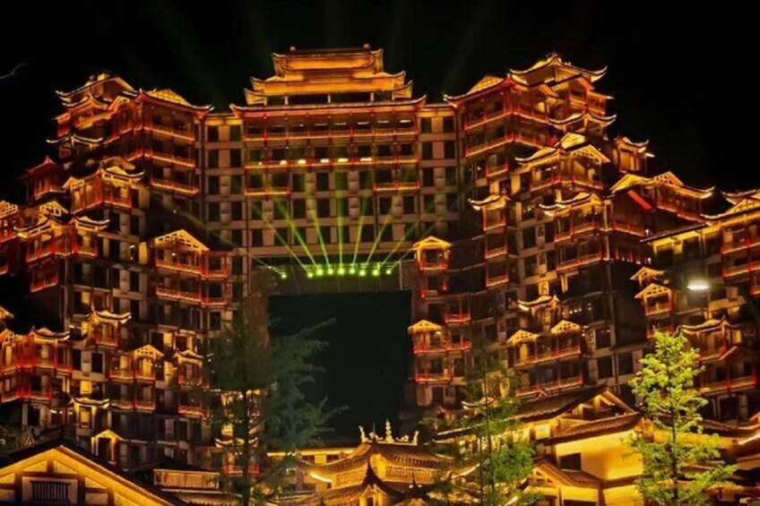 A brightly lit traditional building with multiple tiers and balconies, surrounded by trees. 5