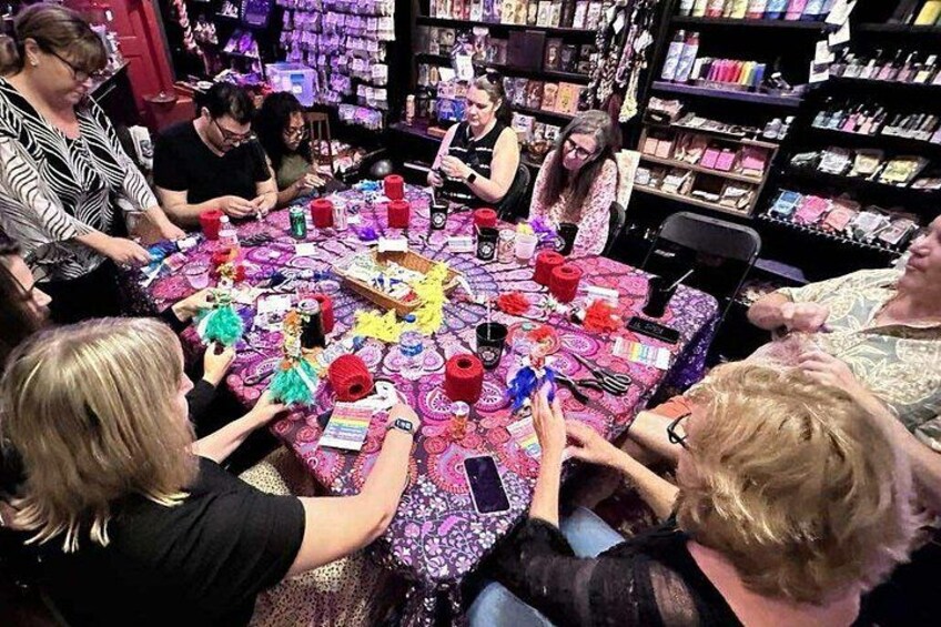 Een groep mensen zit rond een tafel met kleurrijke objecten en een tafelkleed met een patroon. 5