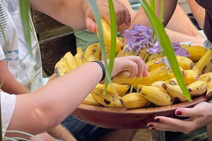 Eine Person hält eine Schale mit Bananen und Blumen. 3