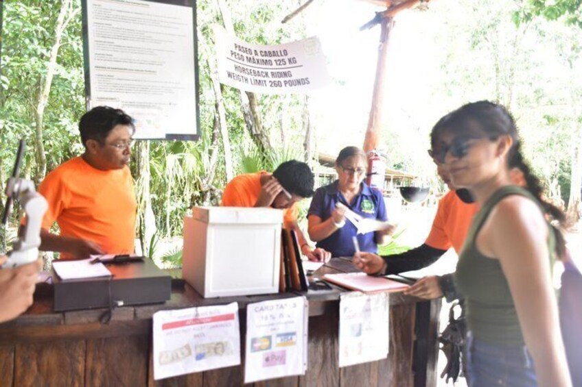 A group of people at an outdoor event with a signboard and a wooden table. 5