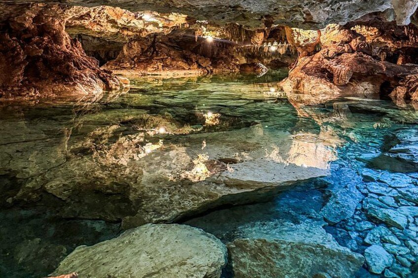 A cave with clear water, rock formations, and a cave entrance. 5
