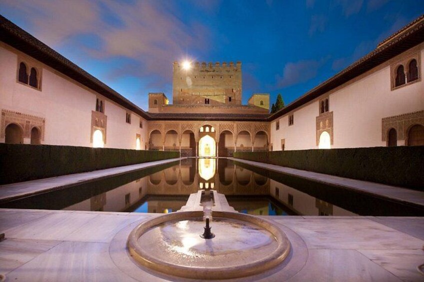 Un patio con una fuente, una piscina y un castillo al fondo. 3