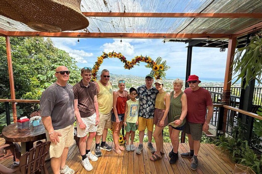 A group of people standing on a wooden deck with a decorative arch made of sunflowers. 2