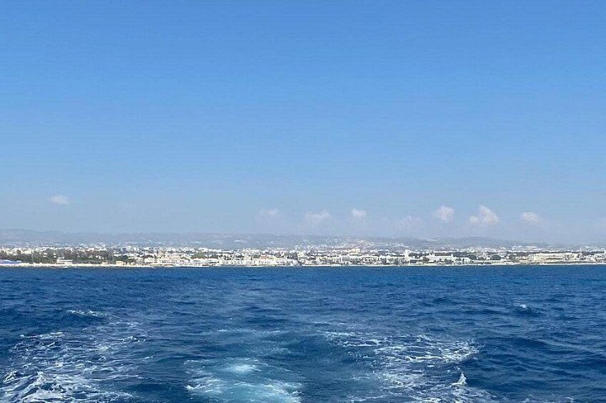 A coastal cityscape with a clear blue sky, calm sea, and distant buildings. 5
