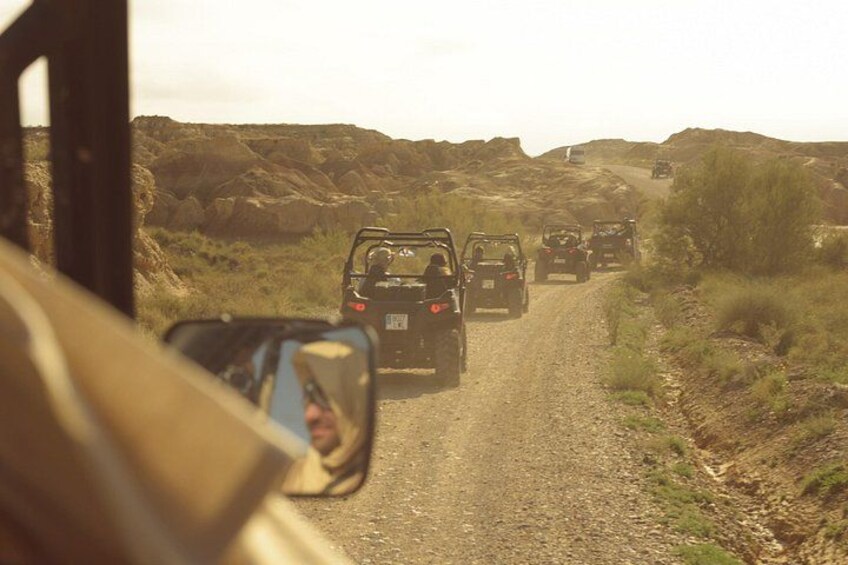 A convoy of off-road vehicles on a dirt road in a rugged landscape. 5