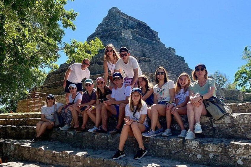 Un grupo de personas sentadas en escalones de piedra con una pirámide al fondo. 1
