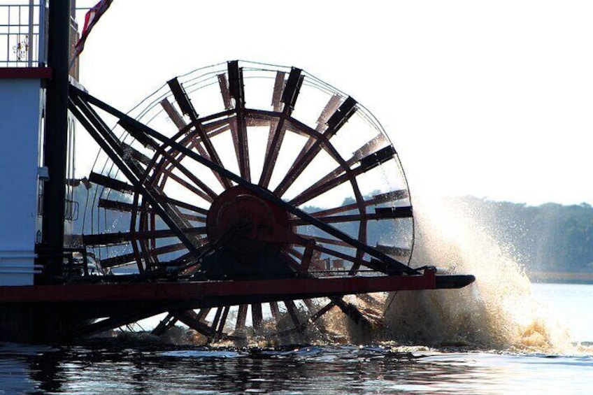 A paddle wheel on a boat, water splashing around it, and a distant shoreline. 5