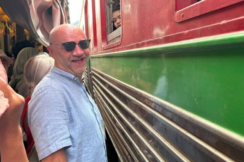 A man standing next to a green and red train. 1
