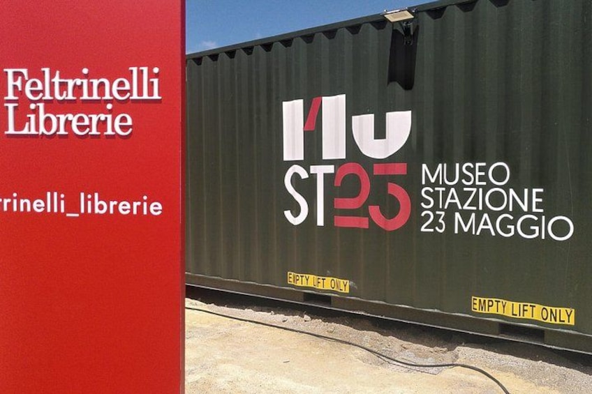 A shipping container with 'MUSEO ST25' and 'MUSEO STAZIONE 23 MAGGIO' written on it. 3