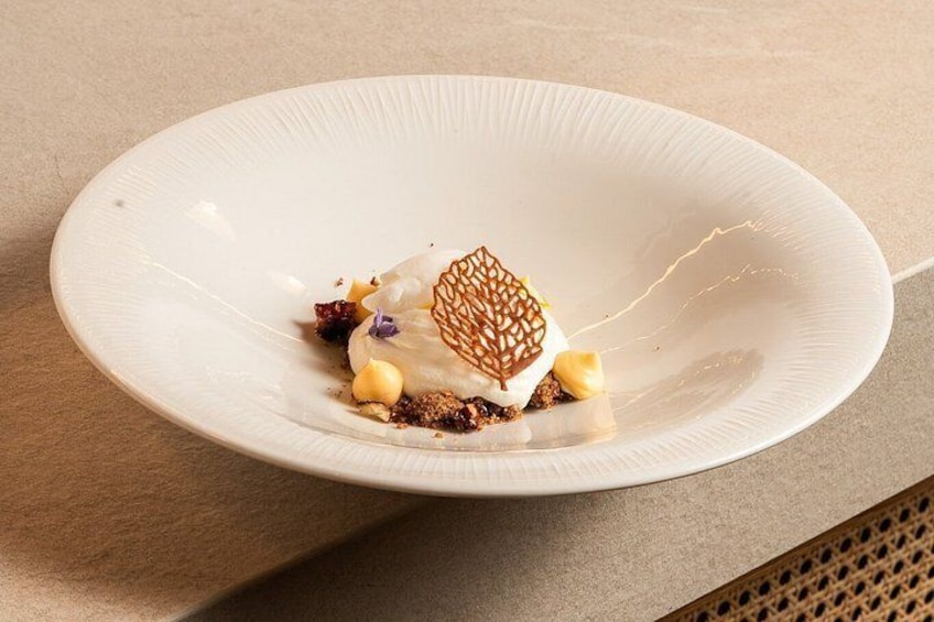 Une assiette blanche sur laquelle est présentée une pâtisserie, le tout posé sur une surface texturée. 3