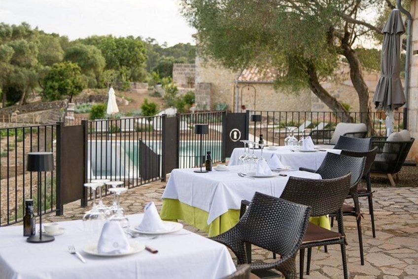 Un espace extérieur aménagé pour les repas, avec des tables pour deux personnes, des chaises et une piscine en arrière-plan. 2