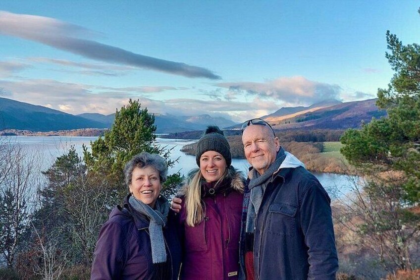 Three people standing by a lake with mountains in the background. 5