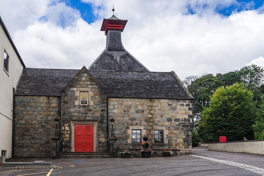 A stone building with a red door, a chimney, and a small garden with flowers. 4