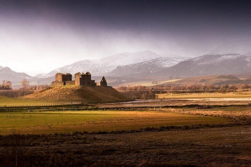 A castle on a hill with a mountainous backdrop. 2