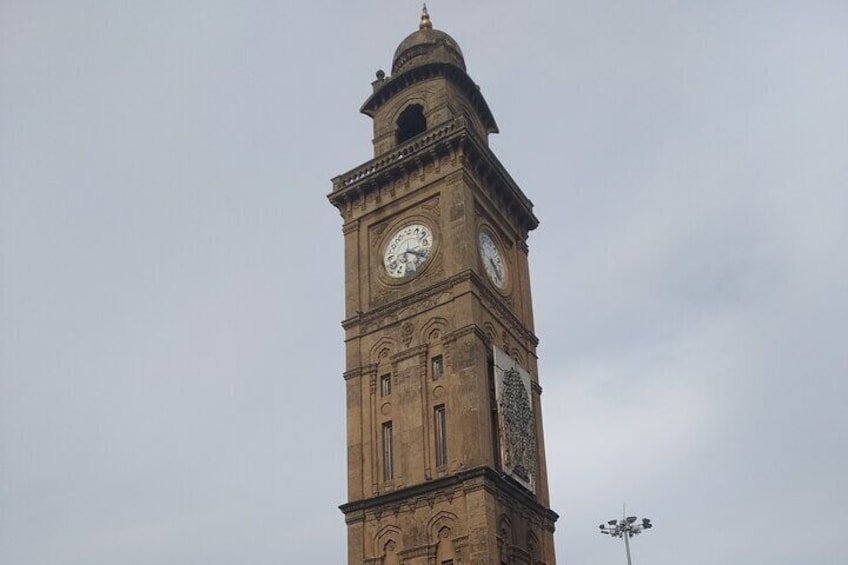 A tall clock tower with two clocks, a dome, and a statue. 4