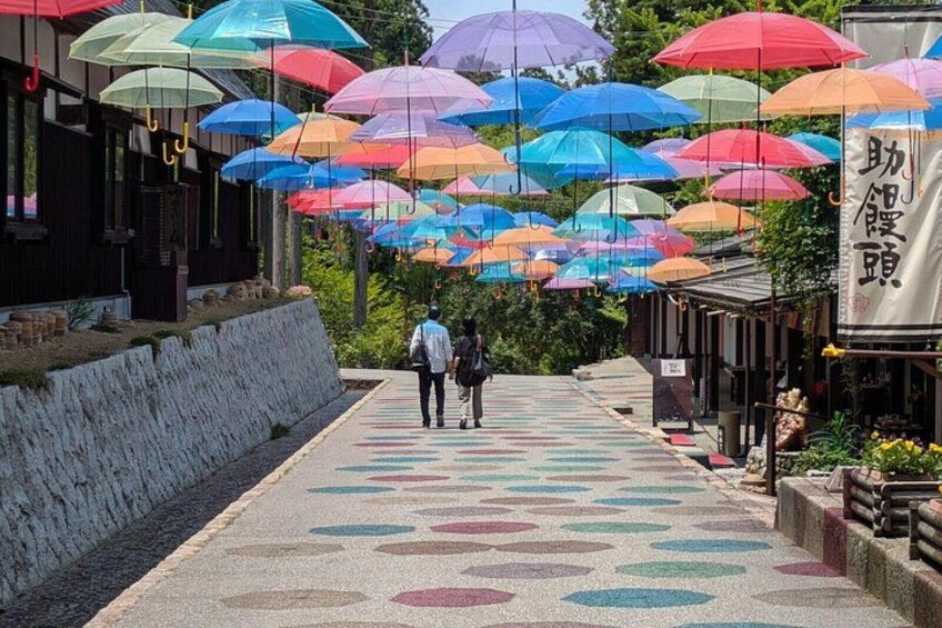 Een pad met kleurrijke parasols erboven en een versierd voetpad. 2