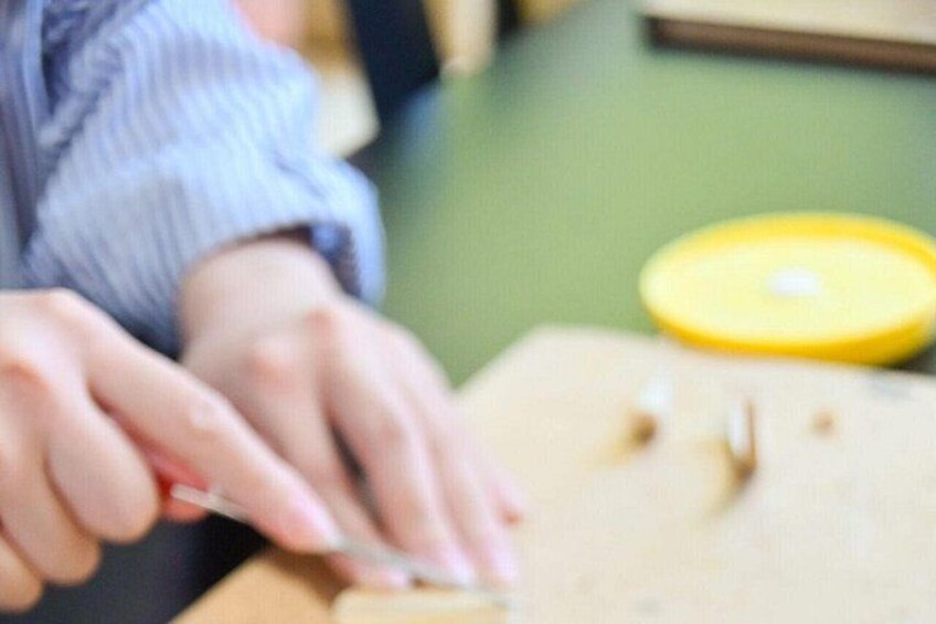 Iemand gebruikt een gereedschap op een houten plank, met een geel voorwerp in de buurt. 4