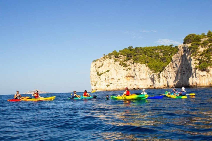 People kayaking on a calm sea with cliffs in the background. 2