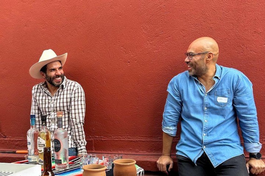 Due uomini seduti a un tavolo con diverse bottiglie e bicchieri. 3