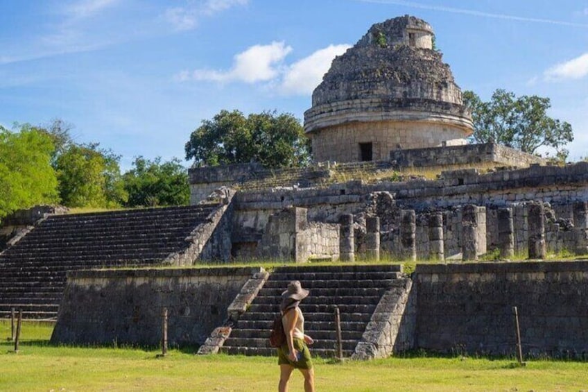 Un'antica piramide con una grande scalinata che vi conduce, circondata da vegetazione lussureggiante. 1