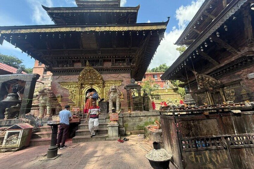 A temple with a golden entrance, steps leading up to it, and statues around. 1