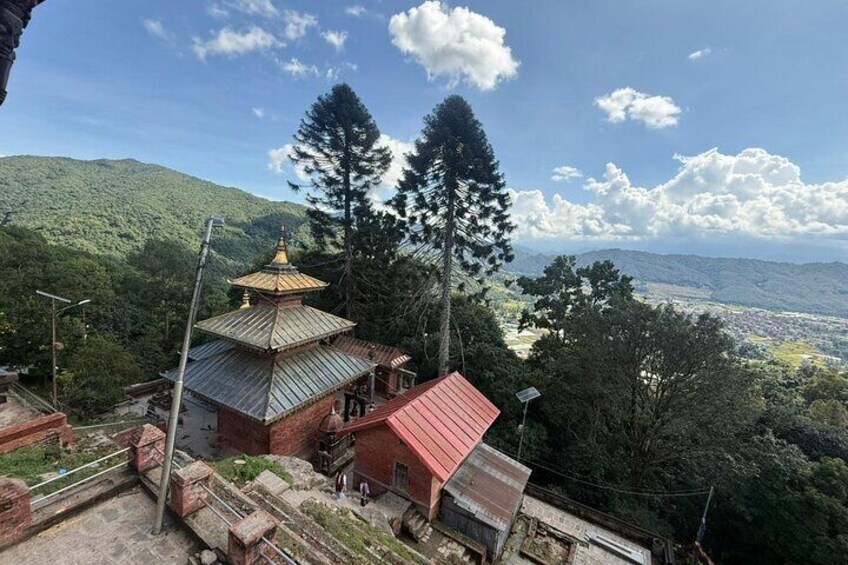 A temple with a red roof, surrounded by lush greenery and mountains in the background. 2