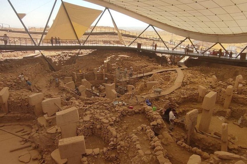 An archaeological site with ancient ruins and a modern structure overhead. 2