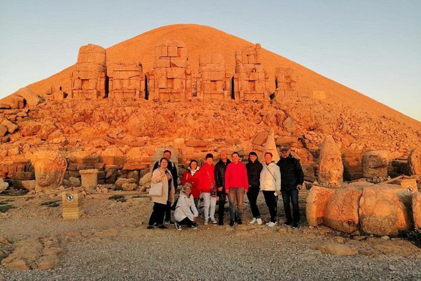 A group of people standing in front of ancient ruins with a large mound in the background. 1