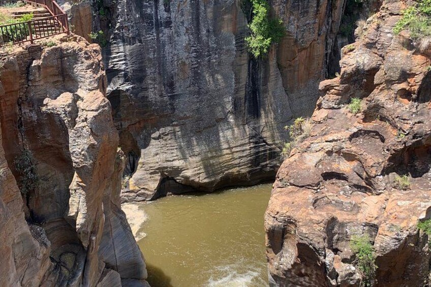 A canyon with a river, rocky cliffs, and a viewing platform. 4