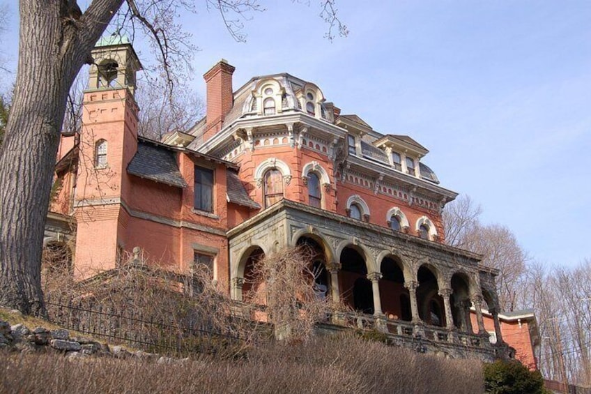 Un grand bâtiment historique à la façade en briques rouges, doté d’arcs au-dessus des fenêtres et surmonté d’une tour imposante. 3