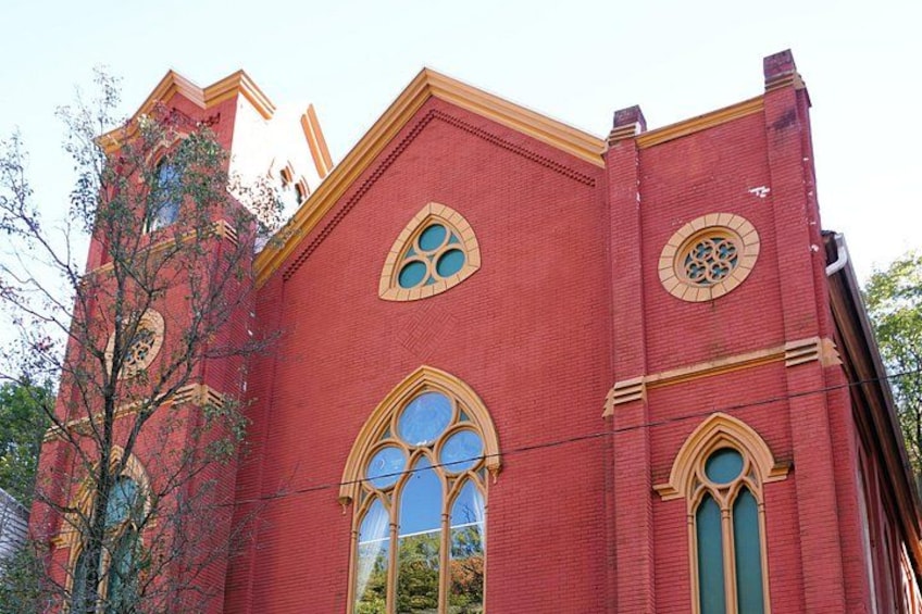Una iglesia de ladrillo rojo con ventanas de arco y una torre del reloj. 4