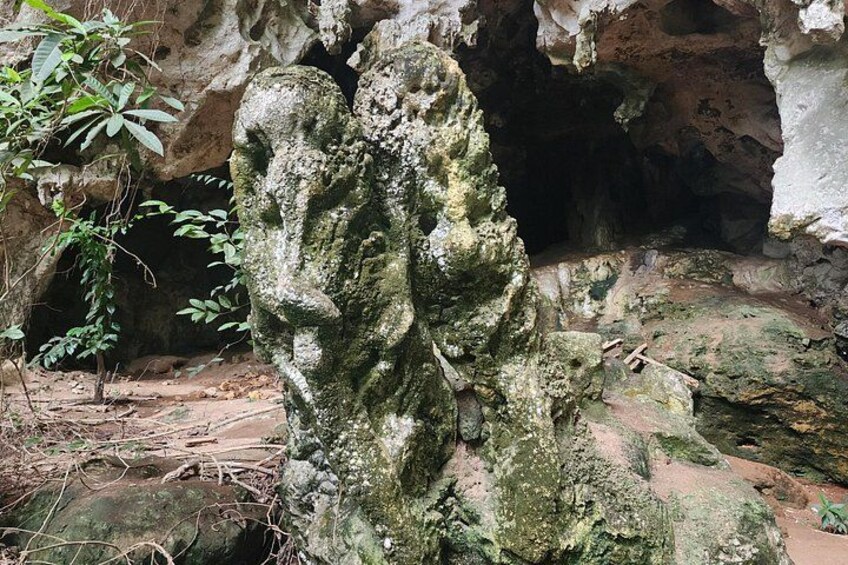 A weathered rock formation with a cave entrance in the background. 3
