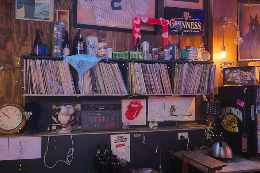 A room with shelves of vinyl records, a clock, and various memorabilia including a Rolling Stones album. 4