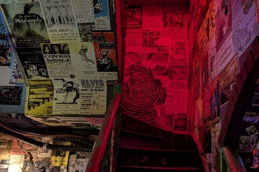 A wall covered with various posters and flyers, including one for 'The Velvet Underground' and 'Elvis'. 5