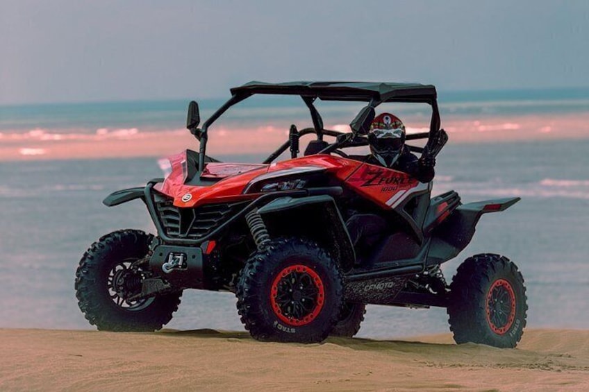 Un quad rouge et noir, arborant le logo « FUTURE », est garé sur une plage, avec l’océan en arrière-plan. 5