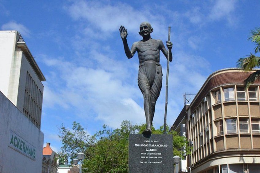 A statue of Mohandas K. Gandhi on a pedestal with a plaque. 4