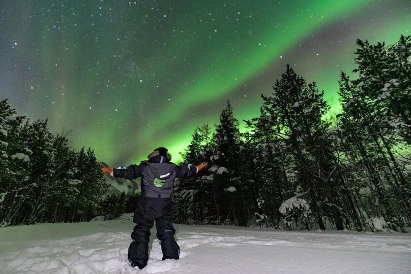 Eine Person steht im Schnee, die Arme ausgestreckt, und blickt den Polarlichtern entgegen. 5
