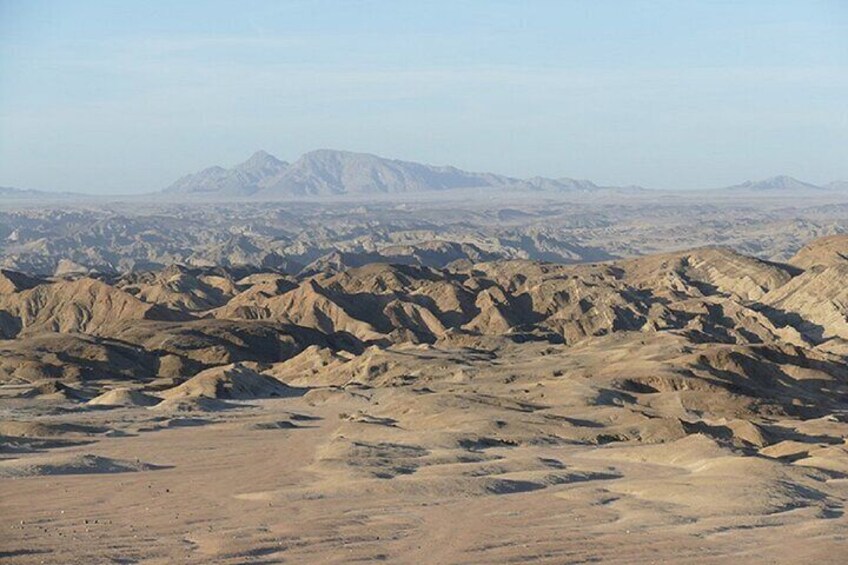 Un extenso paisaje desértico con terreno accidentado y montañas distantes. 3