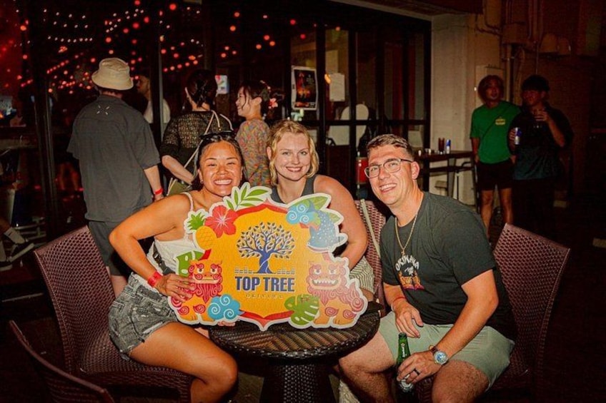 Three people sitting at a table with a colorful poster featuring a tree and the text 'TOP TREE.' 5
